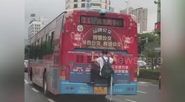 Chinese man spotted clinging onto back of bus moving along road