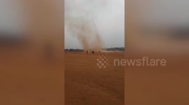 Fearless children run through deep red dust devil tornado in Indonesia