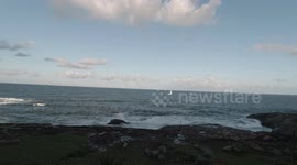 A sail boat in the water next to Santa Luzia Lighthouse