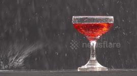 A glass of red wine on a wall in a thunderstorm with heavy rain and sunshine.