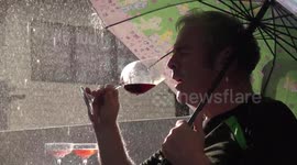 A man sipping and really enjoying a glass of red wine in a thunderstorm, with heavy rain and sunshine.
