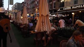 Diners clap and a man curses as Black Lives Matter protesters march past restaurant tables in NYC's Little Italy