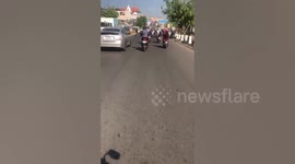 Motorcyclist rides while pushing bike alongside him