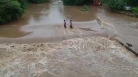 Villagers help each other to cross flooded road using thick ropes in Western India