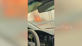 Motorists drive alongside flames from fires in Napa County, California