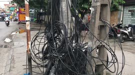 Messy powerline cables wrap around electric pole like a spider web in Vietnam