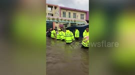 Chinese firefighters stand in deep floodwater to evacuate children from submerged kindergarten
