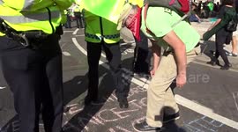 Extinction Rebellion protester draws 'constraint lines' in front of police officers in Parliament Square