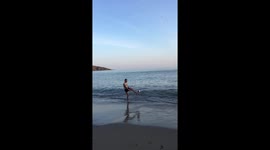 Rugby man kicks ball on beach