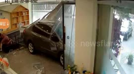 Car narrowly misses woman after smashing into shop in China