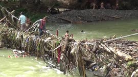 Children clear debris stuck on bridge ruined by heavy flooding in Indonesia
