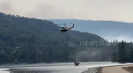 Helicopter picks up water at Bass Lake to fight raging Creek Fire in California