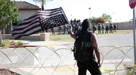 BLM staring down the police unit while holding an upside down American flag.