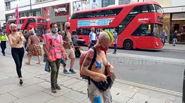 Semi naked Extinction Rebellion protesters march down Oxford Street and glued hands to H&M store window