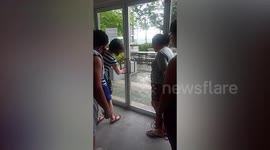 Filipina woman struggles to open door while friends walk through section without glass
