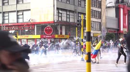 Protesters run as police fire rounds of tear gas during clashes in Bogota