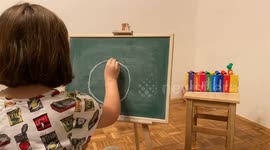 The girl draws a corona virus on the board.  This short video shows how children conceive of the corona virus.