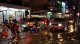 Locals walk home through flooded roads after thunderstorms in Thailand