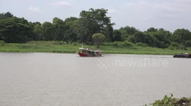 An empty barge and a full one, pass by each other on a river in Thailand.