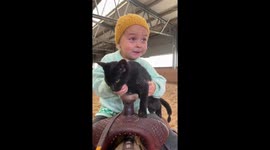 Little toddler rides her ponny with a cat