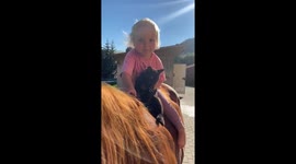 Little toddler rides bareback with her cat