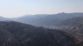 Smoke blankets charred hills ravaged by wildfires in California