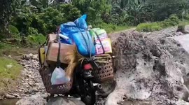 Dedicated teachers ride motorcycle through river to deliver school books in the Philippines