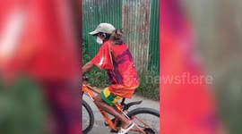 Pet cat rides on owner's shoulders as they cycle home together