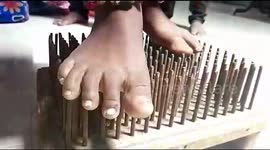Girl standing on a bed of nails and playing drums a bizarre act in Southern India