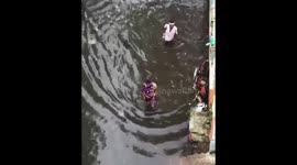people wade through flooded street in india