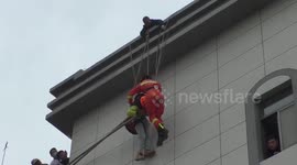 Chinese firefighters rescue paraglider hanging from hotel roof after strong winds blew him towards the building