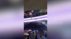 Thai protesters throw umbrellas to help those stuck in the rain