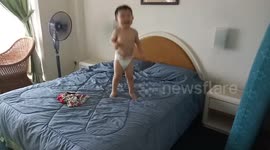 Adorable toddler in weekend mood happily jumping on bed