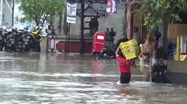 Shop worker falls into hole on flooded road in Bali