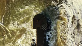 Big Waves Crashing Over Pier - Drone View With Camera Panned Down