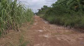 Two people on a motorcycle travel along a very bumpy road full of large potholes.