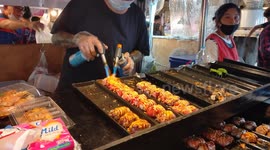 A chef prepares sushi at a local food market using a blow torch.