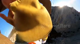 A BASE jumper hangs from a slackline suspended over a sheer drop of almost 1,000 FEET