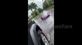 US: Woman Travels Flooded Street On Inner Tube After Storm Eta