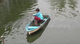 Fishing Thai style in a small boat without a paddle.