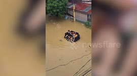 Three men float on inflatable sofa after Typhoon Vamco causes floods in the Philippines