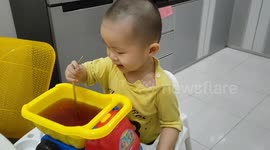 Funny toddler enjoys to drink from his truck toy