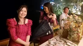 Wedding guests hold umbrellas over bride and groom during rainstorm in Thailand