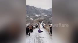 Hundreds of tourists slip and slide as they struggle to climb the Great Wall of China