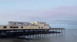 Thousands of starlings burst out from under The Royal Pier, in a spectacular murmuration, West Wales, Uk