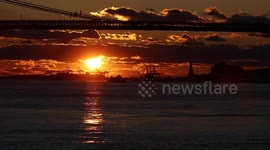 New York skyline turns orange as sun sets behind Statue of Liberty