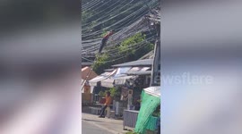 Repairman tight-rope walks along electricity cables while carrying out repairs
