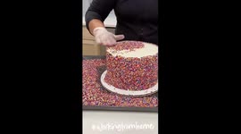 Home baker shows satisfying technique to cover a cake in sprinkles