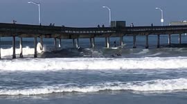 Surfers catch waves under San Diego Pier on Thanksgiving