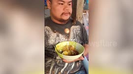 Bird joins Thai man eating noodles
